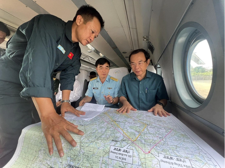 Bí thư Nguyễn Văn Nên (bìa phải) xem bản đồ hành trình bay khảo sát - Ảnh: TIẾN LONG