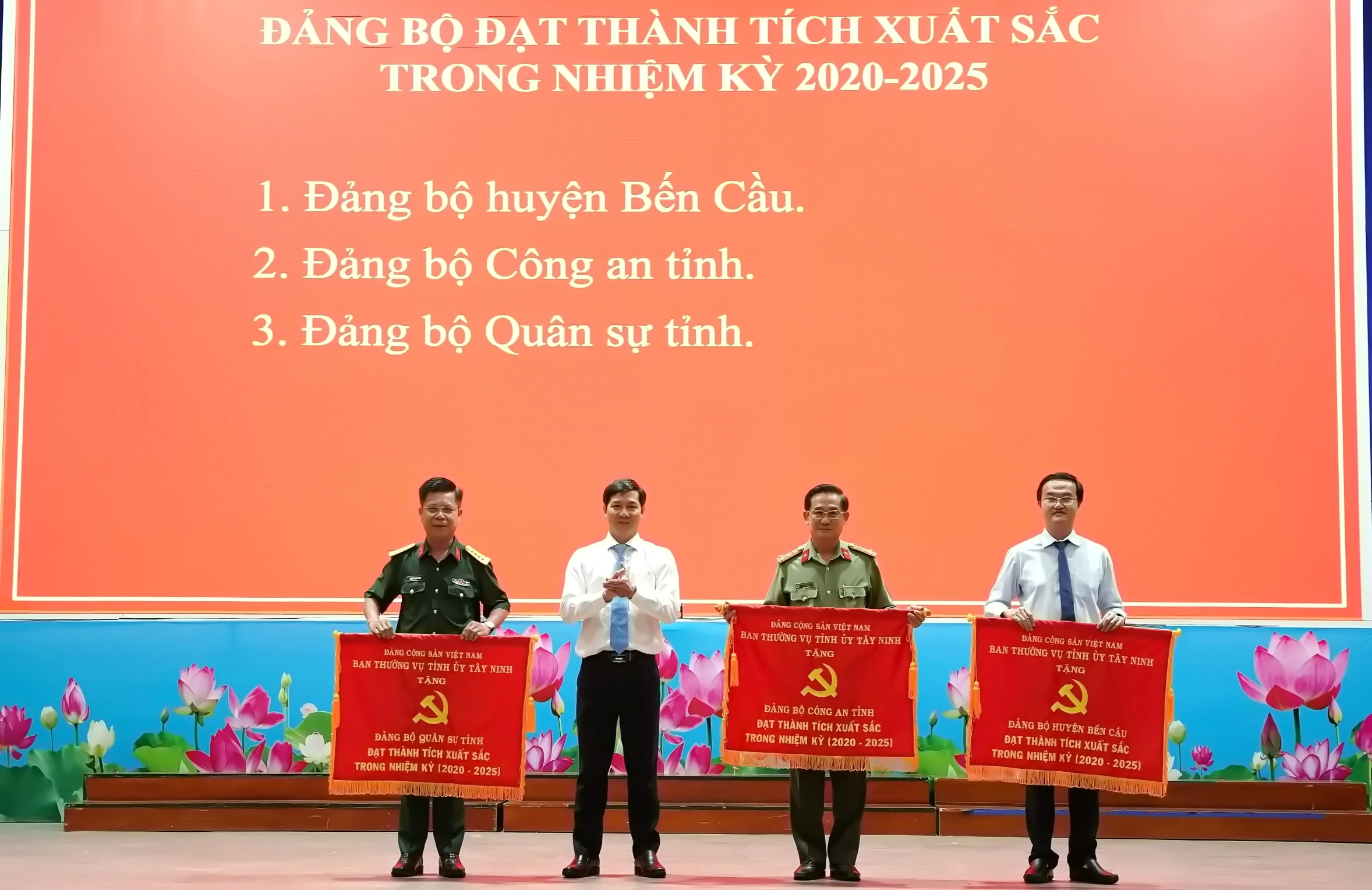 Đồng chí Nguyễn Thành Tâm- Uỷ viên Ban Chấp hành Trung ương Đảng, nguyên Bí thư Tỉnh uỷ, Chủ tịch Hội đồng nhân dân tỉnh tặng cờ thi đua cho 3 đảng bộ đạt thành tích xuất sắc trong nhiệm kỳ 2020-2025. Trong ảnh, đồng chí Phan Huỳnh Quốc Vinh- Bí thư Huyện uỷ Bến Cầu (bìa phải) nhận cờ thi đua.