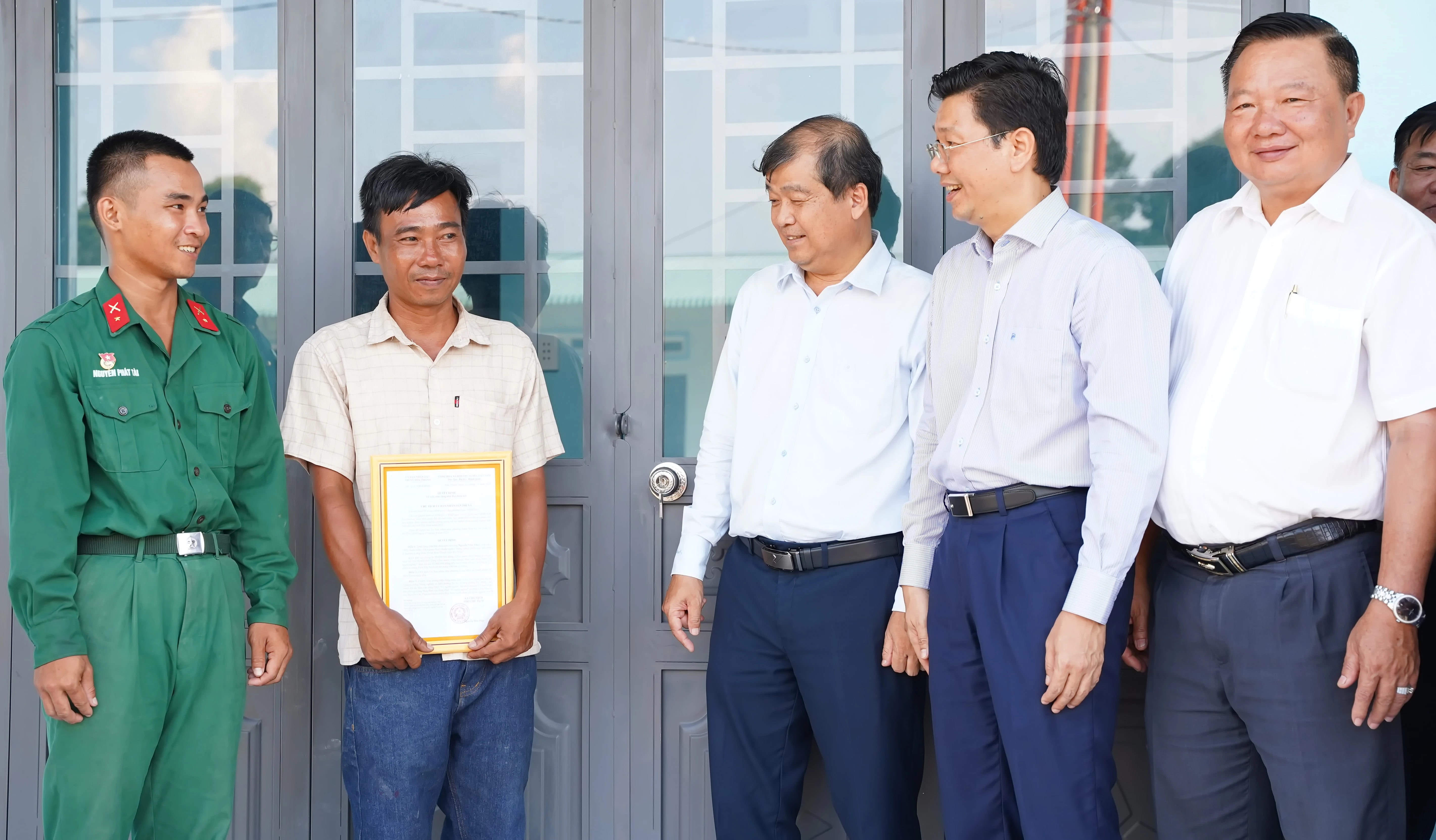 Bí thư Tỉnh uỷ, Chủ tịch HÐND tỉnh Nguyễn Mạnh Hùng (thứ hai từ phải sang) và Chủ tịch UBMTTQ Việt Nam tỉnh Võ Ðức Trong (giữa) trò chuyện với hộ gia đình được tặng nhà Ðại đoàn kết. Ảnh: Phương Thuý