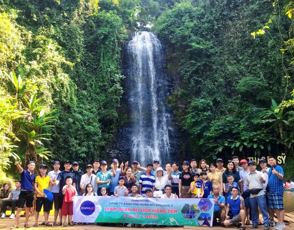 A group of people posing for a photo in front of a waterfallDescription automatically generated