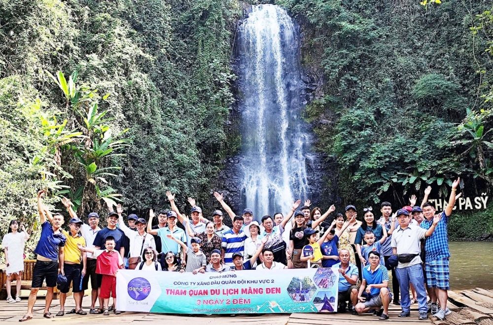 A group of people posing for a photo in front of a waterfallDescription automatically generated